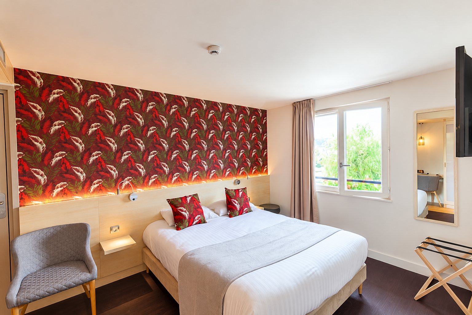 Chambre lumineuse avec lit double et papier peint tropical rouge