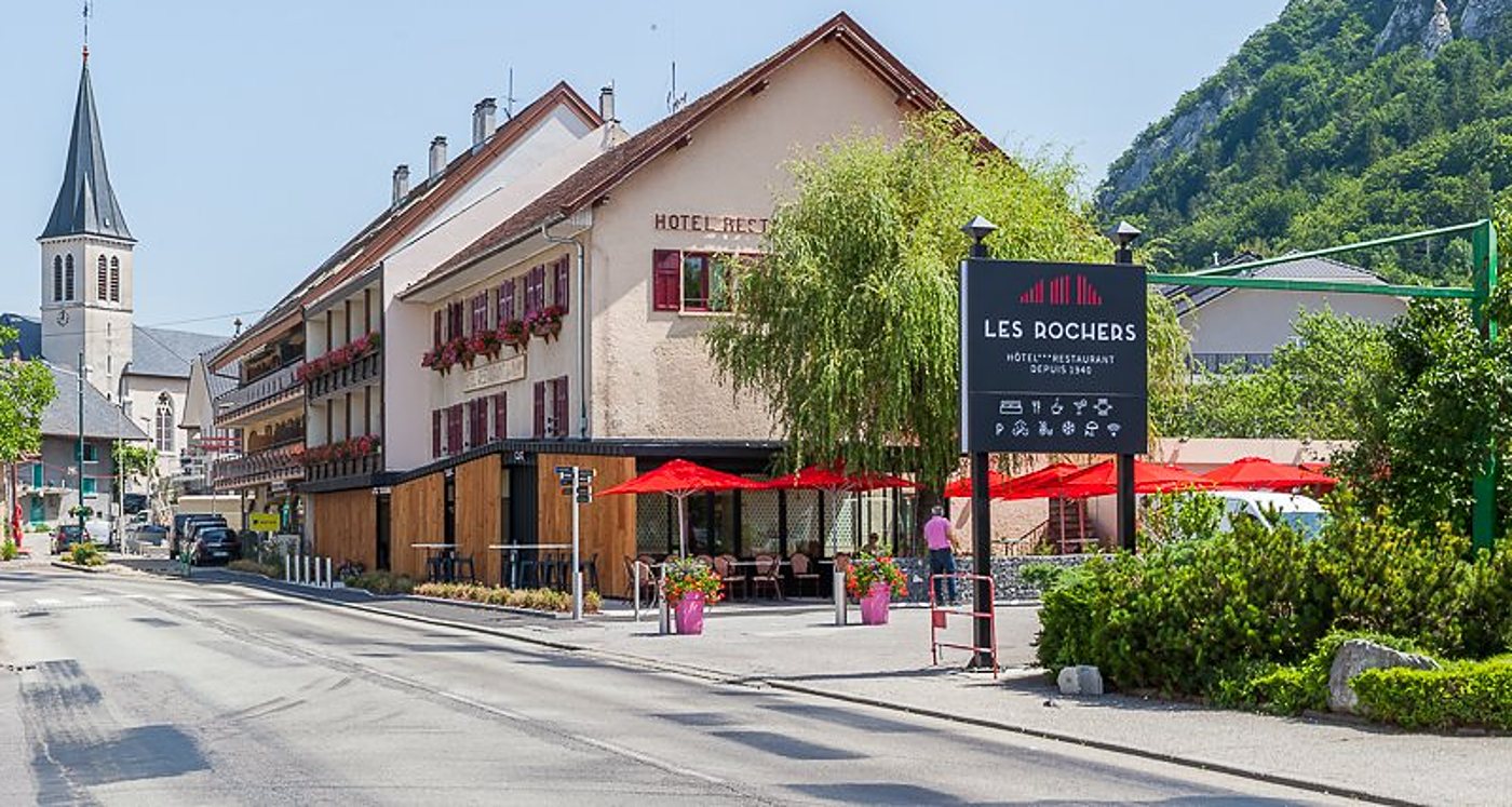 Façade de l'hôtel Les Rochers avec la terrasse et la montagne